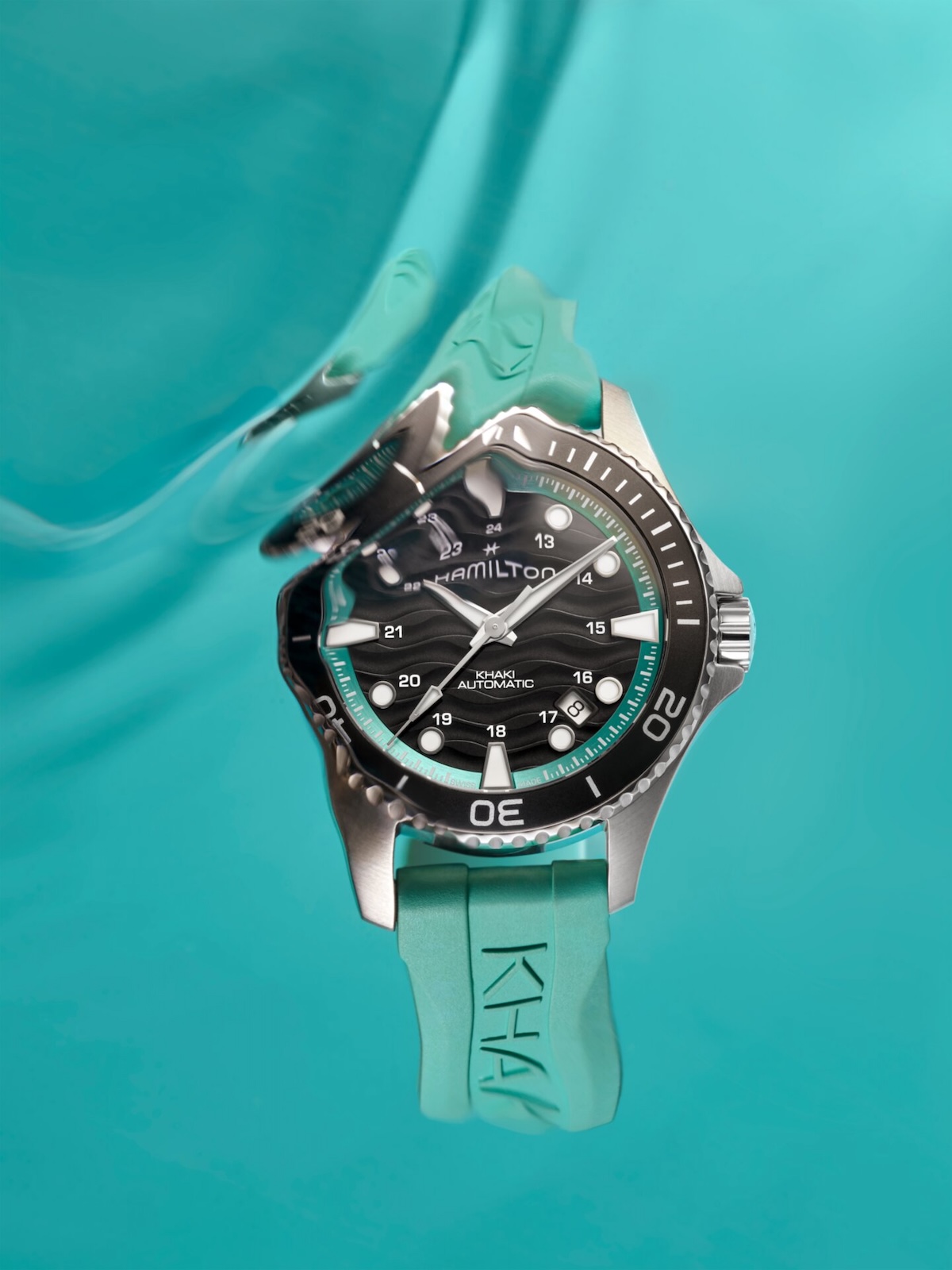 Hamilton Khaki Navy Scuba Auto 40mm with turquoise rubber strap and wave-textured black dial against a teal water background