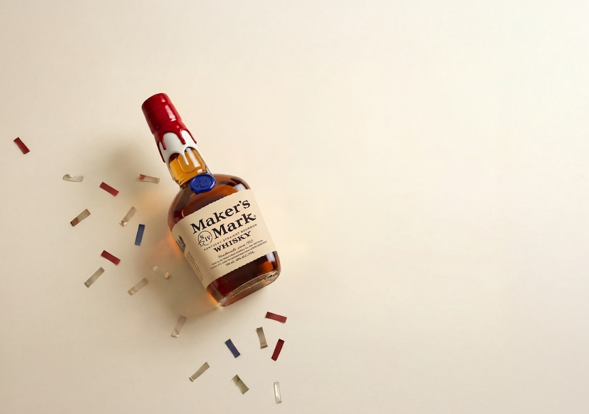 Maker's Mark 250th Anniversary limited edition bottle showing red wax overlaid in white with blue seal and red white blue confetti on cream backdrop